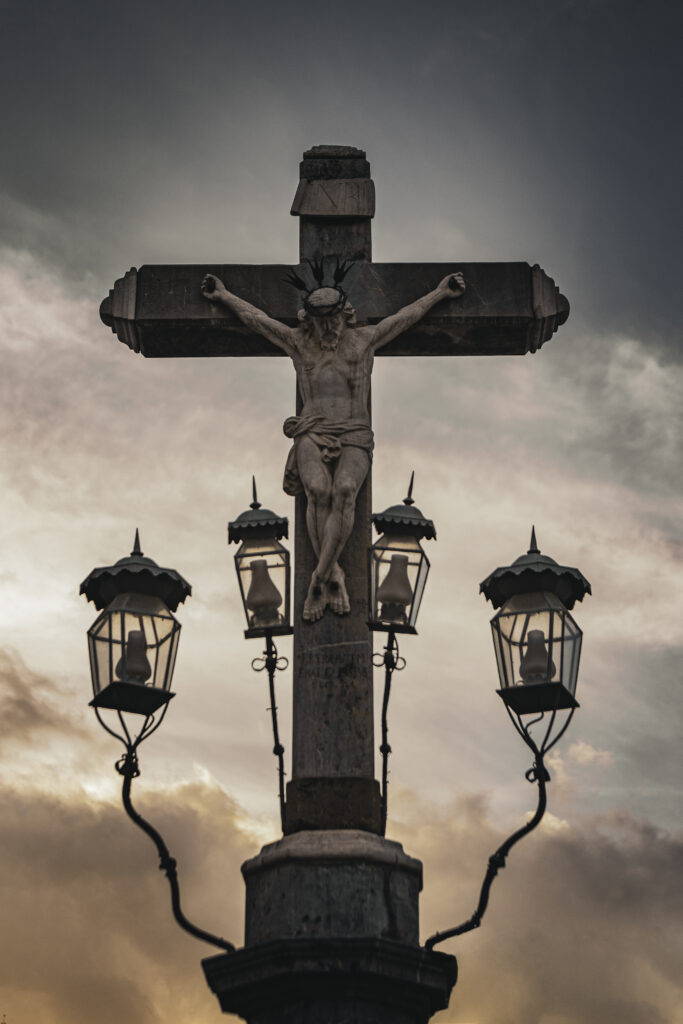 Escultura del Cristo de los Faroles iluminada en la Plaza de Capuchinos de Córdoba, rodeada por faroles de hierro forjado