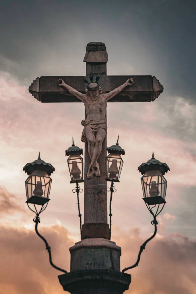 Escultura del Cristo de los Faroles iluminada en la Plaza de Capuchinos de Córdoba, rodeada por faroles de hierro forjado