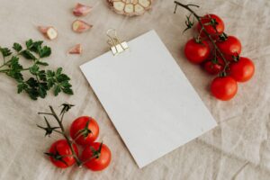 Mesa con ingredientes mediterráneos: tomates cherry, ajo y perejil, junto a una tarjeta en blanco para presentar los platos típicos de Córdoba