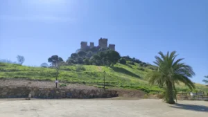 Vista diurna del Castillo de Almodóvar del Río, una fortaleza medieval de piedra con almenas y torres cuadradas, situada en la cima de una colina.
