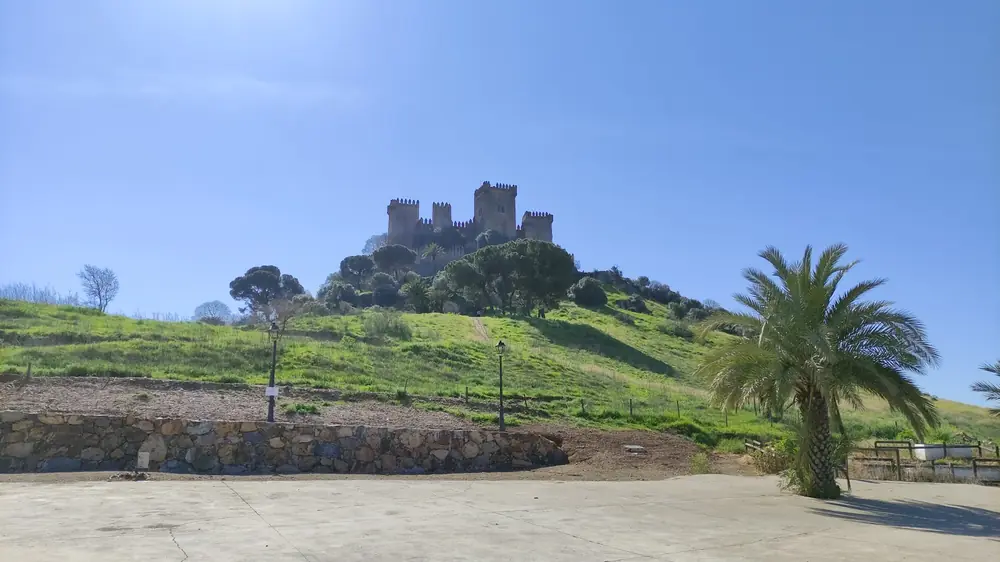 Vista diurna del Castillo de Almodóvar del Río, una fortaleza medieval de piedra con almenas y torres cuadradas, situada en la cima de una colina.