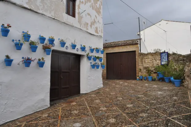 Muro encalado de Iznájar cubierto de macetas azules