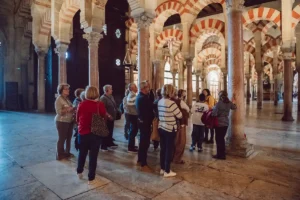 Adela Calzado, guía oficial de la Mezquita-Catedral de Córdoba, explicando el monumento a un grupo de jubilados entre los arcos bicolores de la sala de oración